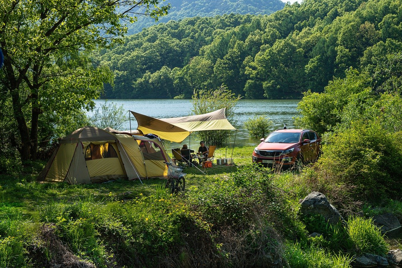 Tent and camping setup beside a forest lake